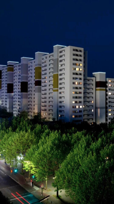 Beleuchtete, moderne Hochhäuser bei Nacht im Märkischen Viertel.